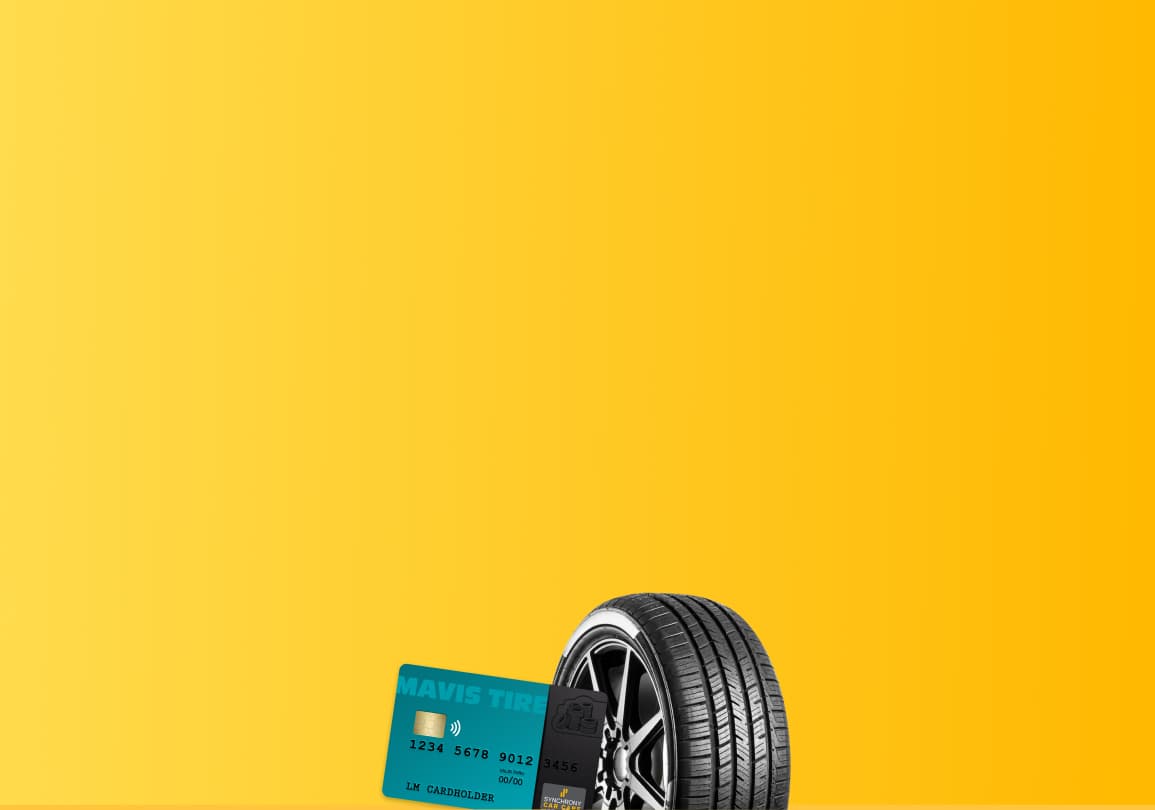Black tire with chrome rim next to a teal credit card on a bright yellow background.